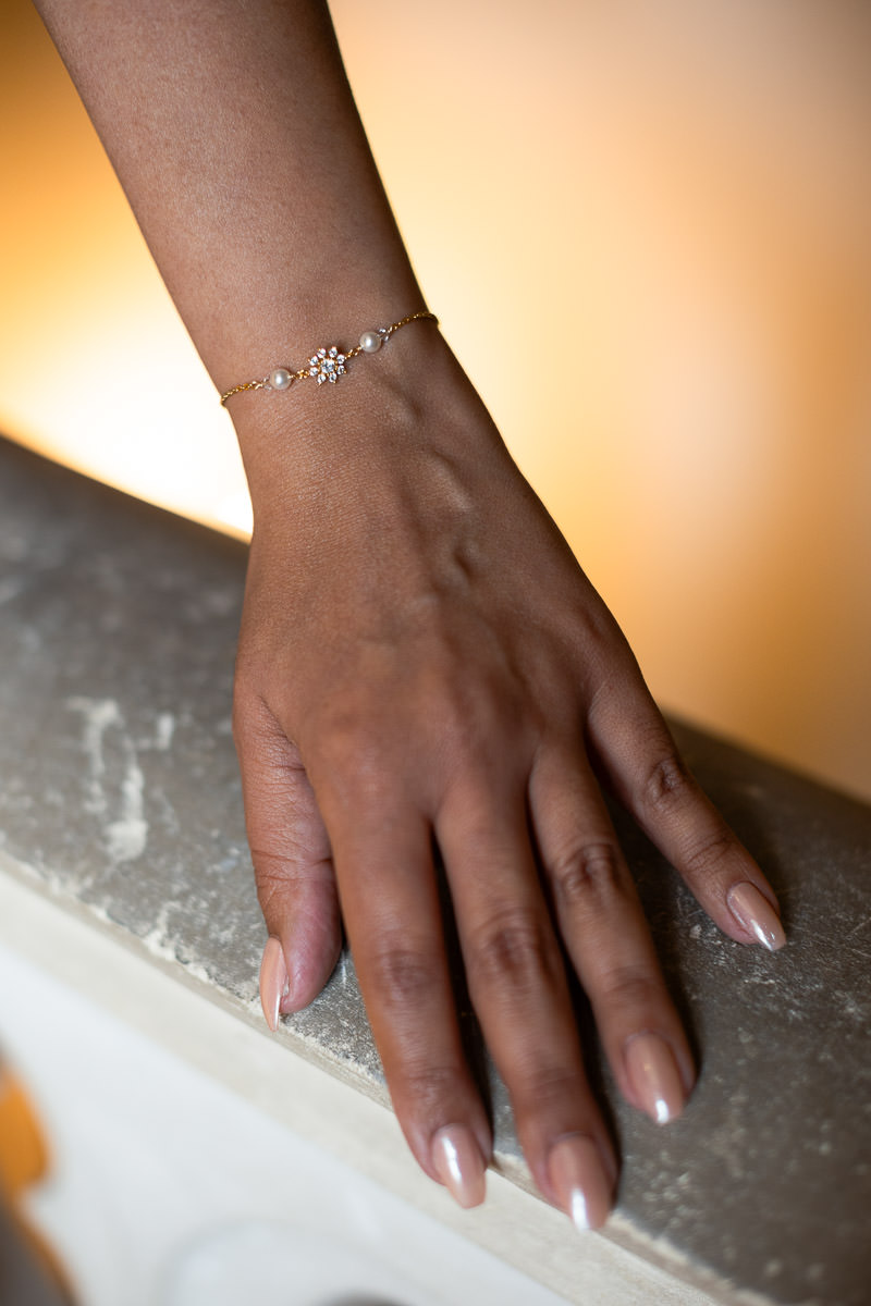 main de mariée avec joli vernis à ongles et bracelet de perles